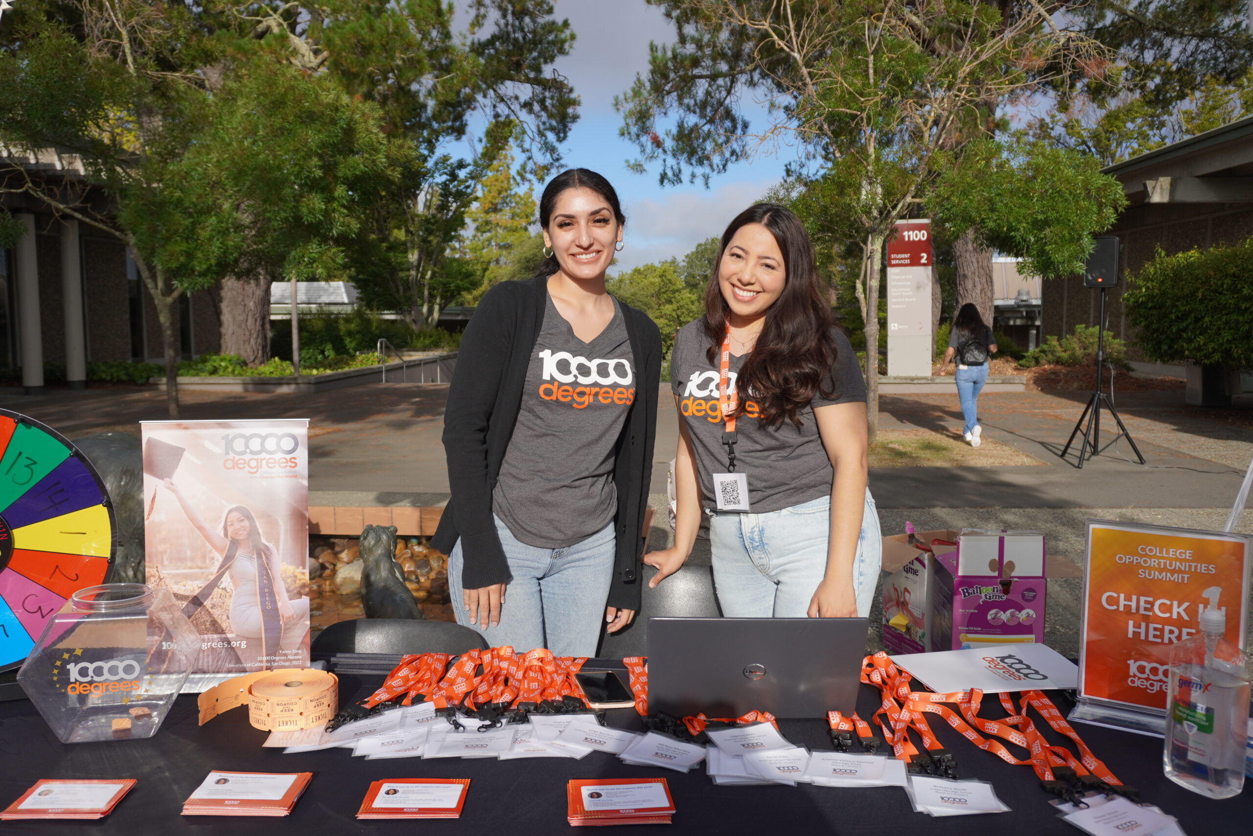 Two women at college event booth with materials.