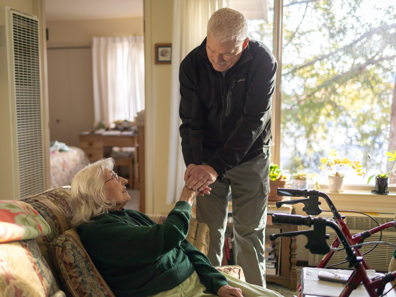 Elderly woman receiving support from caregiver at home.