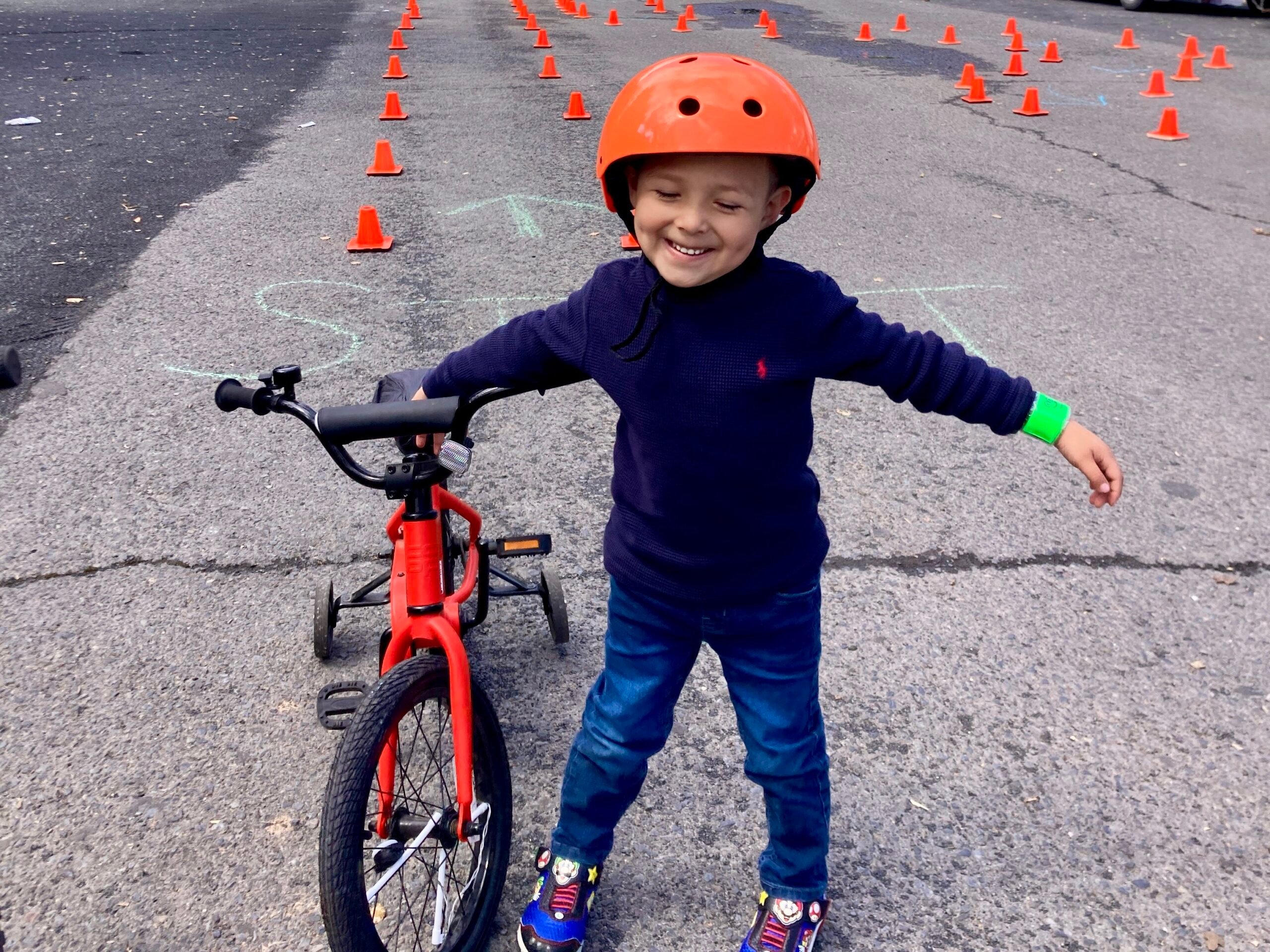 Child with helmet riding bicycle near cones.