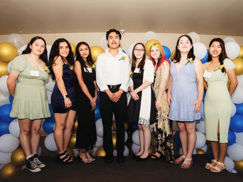 Group posing with themed balloon backdrop.