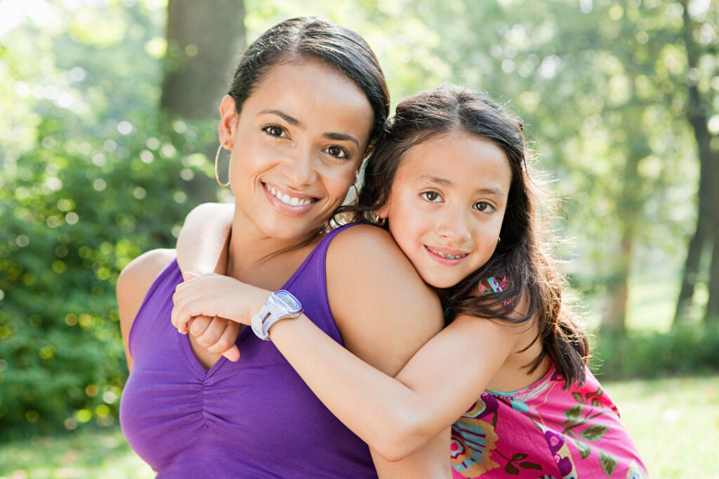 Smiling woman and girl hugging outdoors