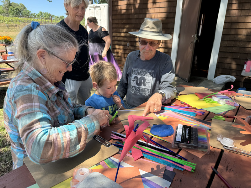 Family crafting outdoors with colorful materials.