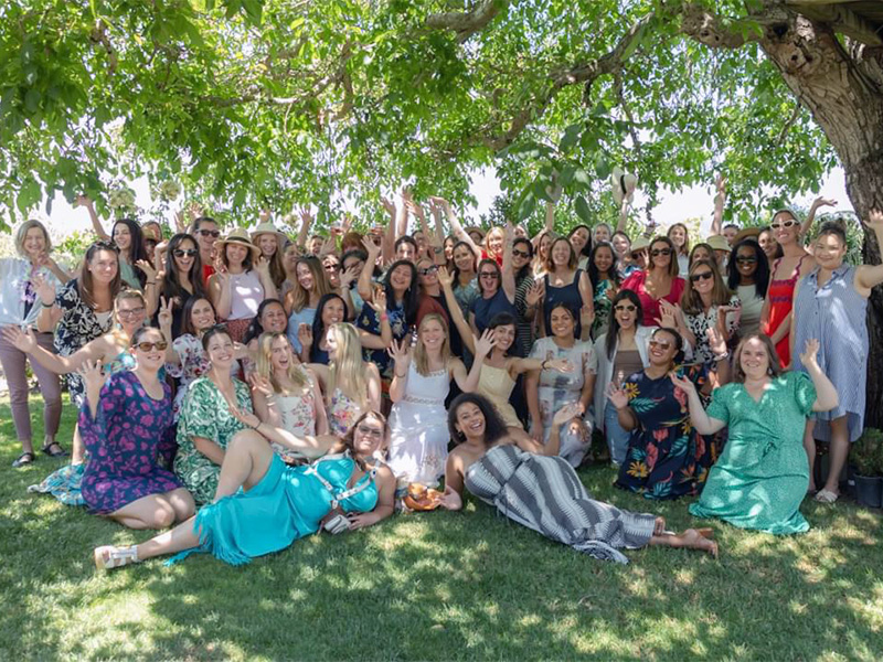 Group of women gathered under a tree outdoors.