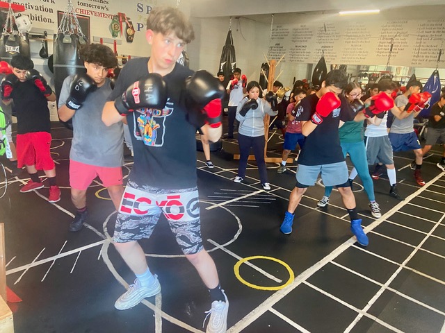 Group boxing training in gym with colorful floor mats.