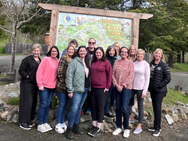 Group of women in front of sign outdoors.