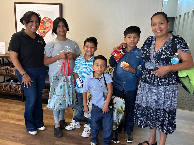 Smiling family holding bags and snacks indoors.